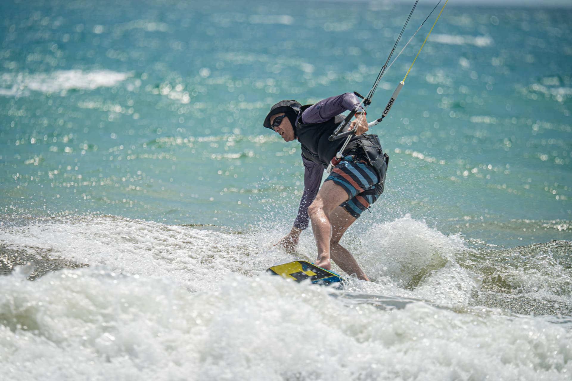 Two kitesurfers riding across the water with three kites overhead